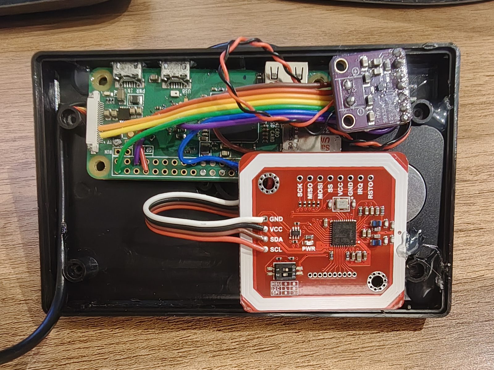 O Alexo aberto: o Pi Zero, a placa de áudio roxa, o leitor NFC vermelho e o alto-falante no canto