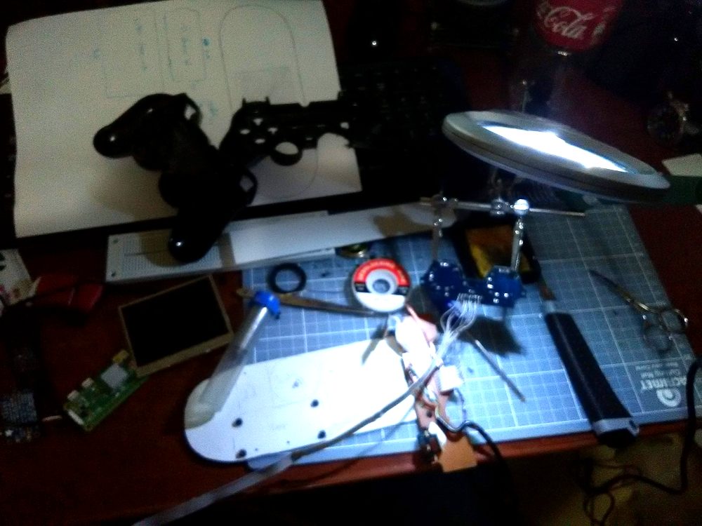 A mesa no meio da montagem: o molde riscado no PVC, a carcaça já furada, a placa do Pi e a telinha