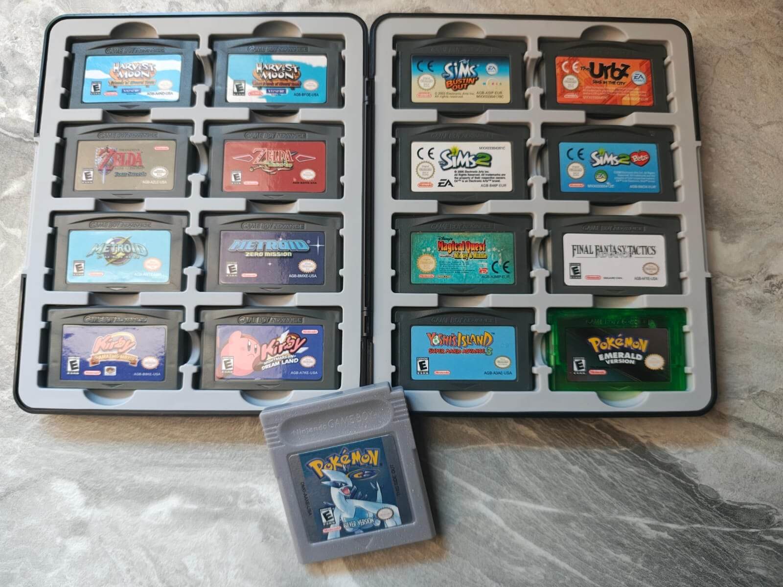 Estojo aberto com dezesseis cartuchos de GBA e um cartucho de Pokémon Silver de Game Boy na frente